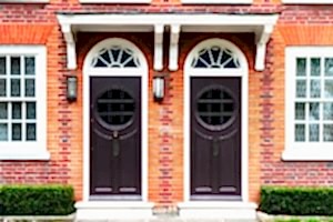 Twin Arched Dark Doors in Red Brick Wall with White Details